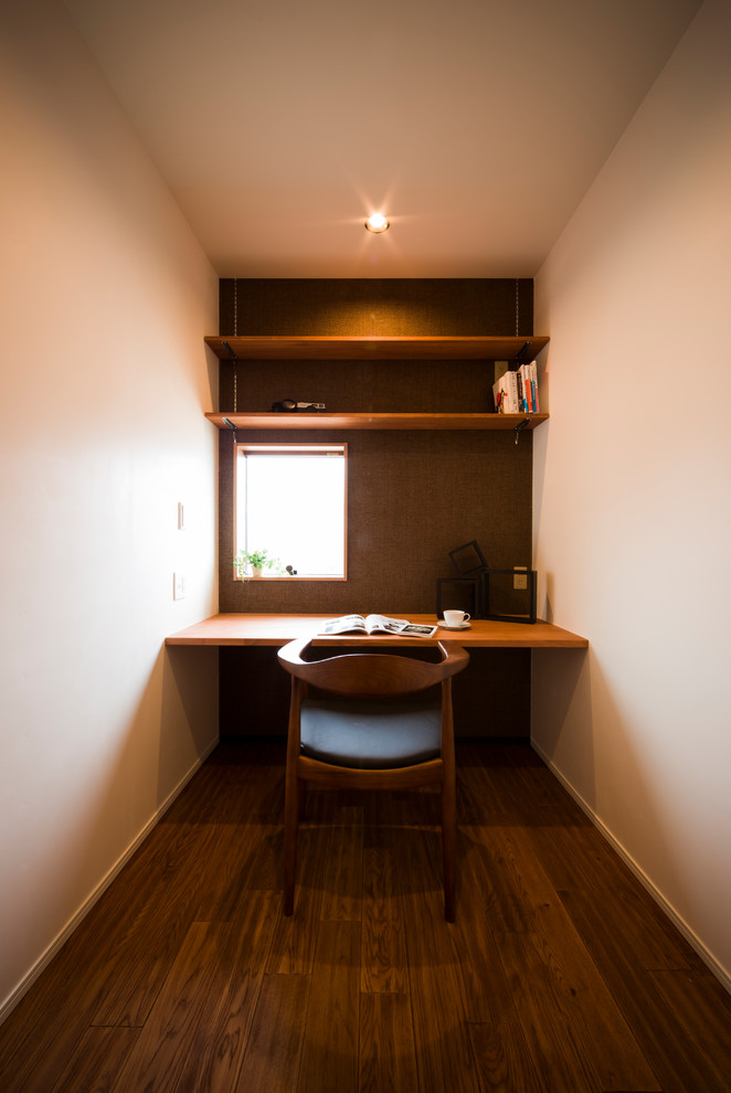 Cette photo montre un bureau craftsman avec un mur beige, parquet foncé, un bureau intégré et un sol marron.