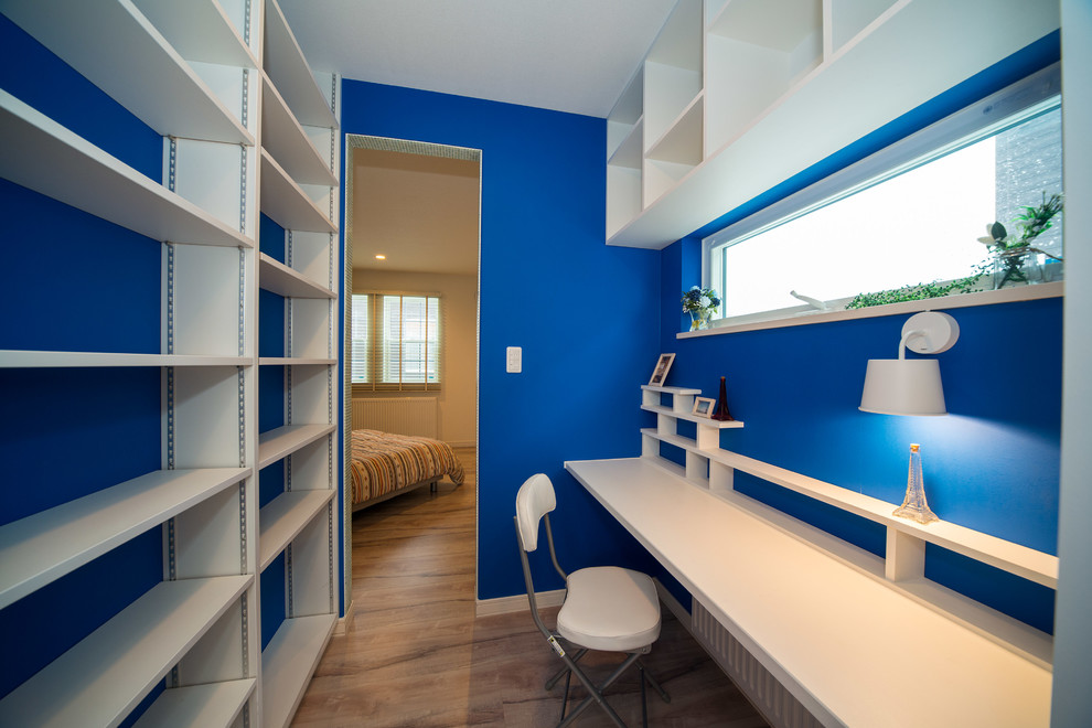 他の地域にあるトランジショナルスタイルのおしゃれなホームオフィス・書斎 (青い壁、造り付け机、無垢フローリング) の写真
