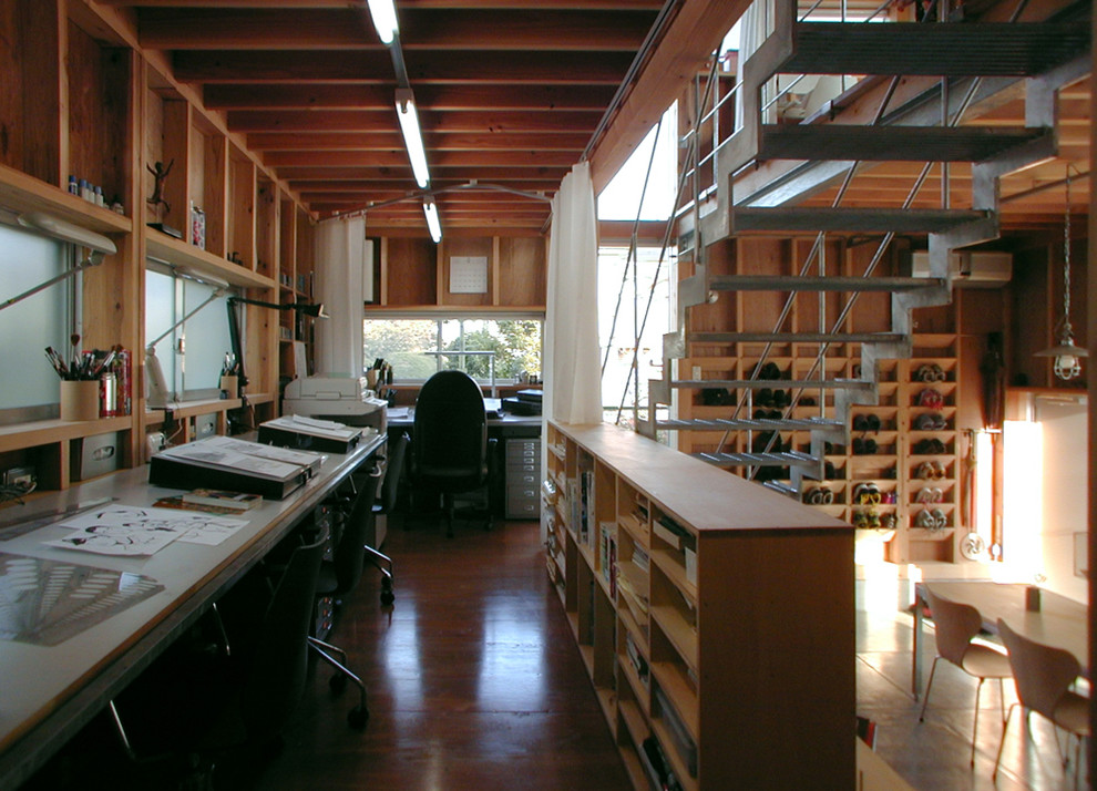 Idéer för mellanstora industriella hemmabibliotek, med bruna väggar, mörkt trägolv och ett inbyggt skrivbord