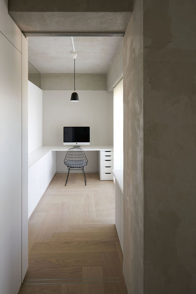 Industrial Arbeitszimmer mit weißer Wandfarbe, gebeiztem Holzboden, Einbau-Schreibtisch und beigem Boden in Tokio