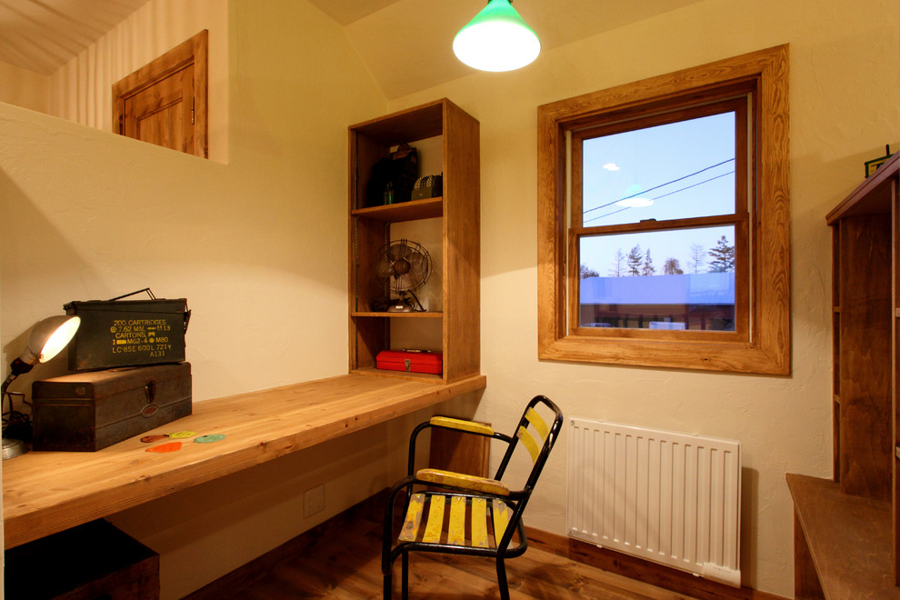 Cette image montre un bureau asiatique avec un mur blanc, un sol en bois brun, un bureau intégré et un sol marron.