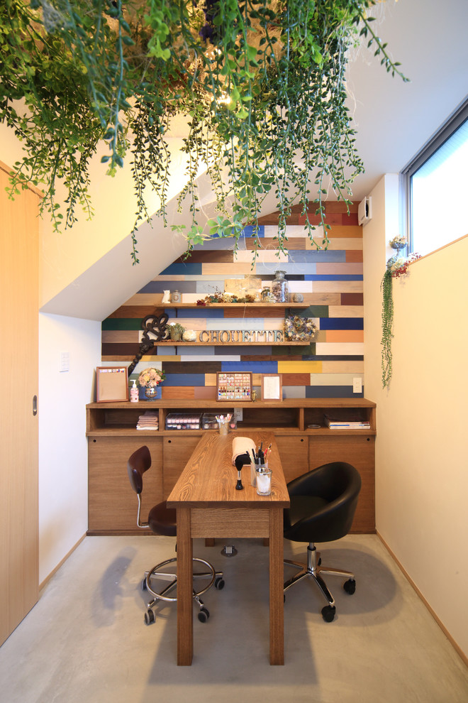Kleines Modernes Arbeitszimmer mit Arbeitsplatz, bunten Wänden, Betonboden und freistehendem Schreibtisch in Nagoya