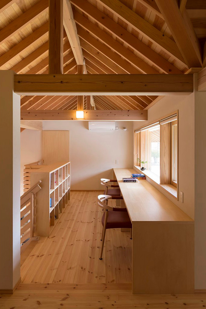 Idee per uno studio etnico con pareti bianche, pavimento in legno massello medio, scrivania incassata e pavimento marrone