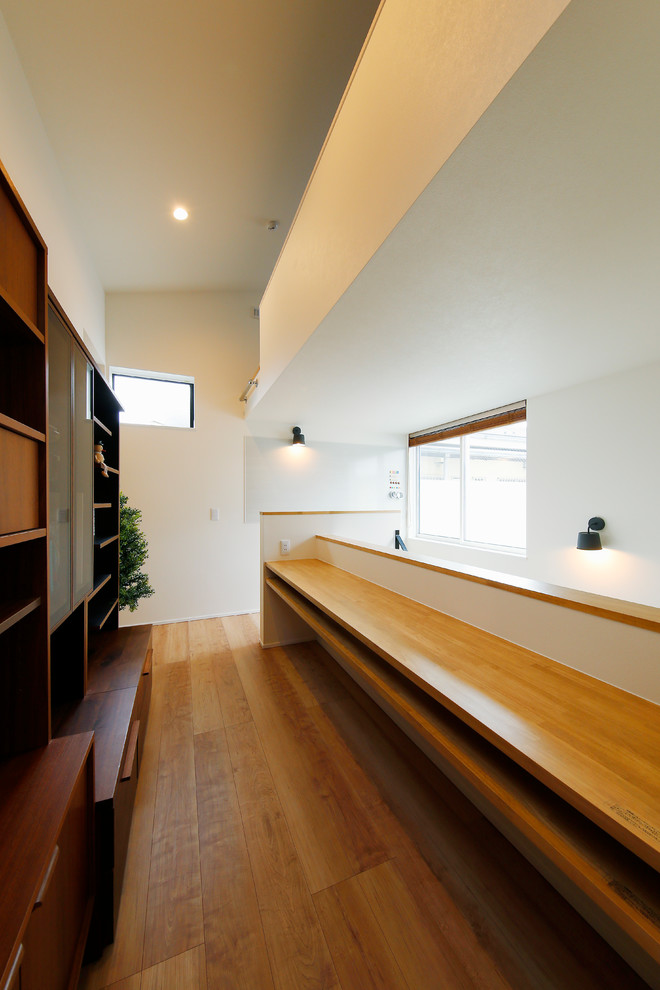 Mid-sized danish built-in desk medium tone wood floor and brown floor study room photo in Tokyo with white walls