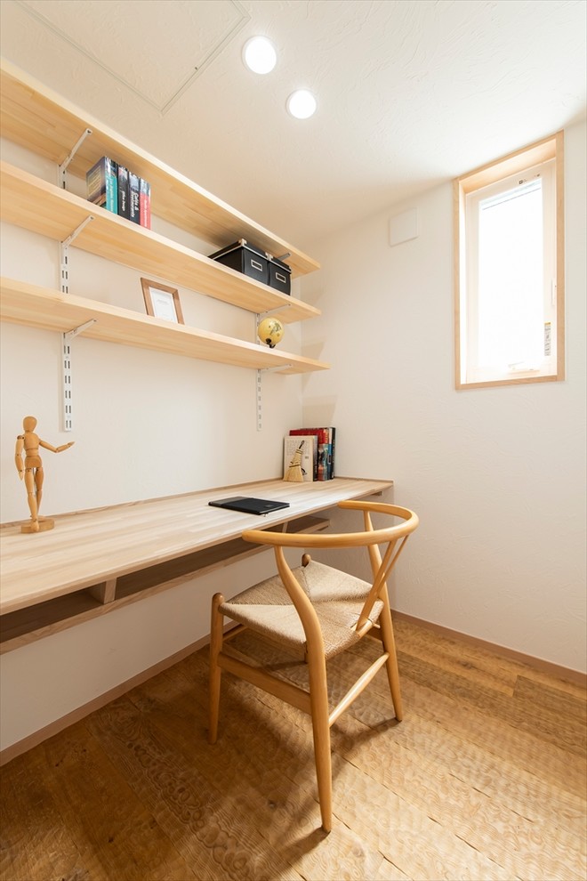 Modelo de despacho de estilo zen con paredes blancas, suelo de madera en tonos medios, escritorio empotrado y suelo marrón