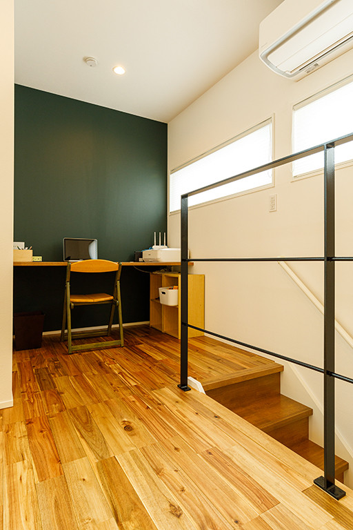 東京都下にあるお手頃価格の中くらいなインダストリアルスタイルのおしゃれな書斎 (緑の壁、無垢フローリング、造り付け机、茶色い床) の写真