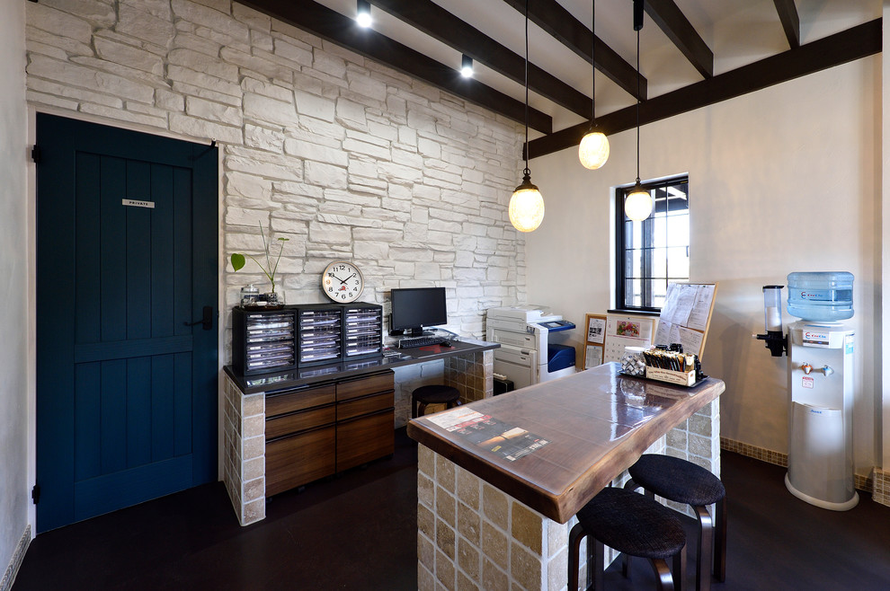Ejemplo de despacho industrial de tamaño medio con paredes beige, escritorio independiente y suelo negro