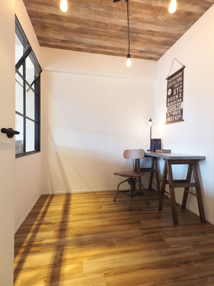 Exempel på ett litet industriellt arbetsrum, med vita väggar, mellanmörkt trägolv, ett inbyggt skrivbord och brunt golv