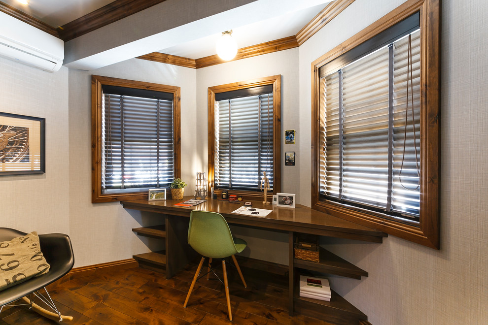 Immagine di uno studio contemporaneo con pareti bianche, pavimento in legno verniciato, scrivania incassata e pavimento marrone