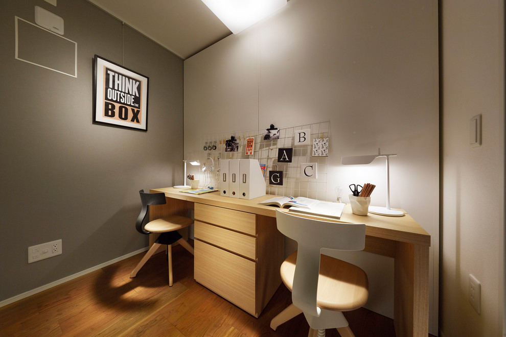 Idée de décoration pour un bureau design avec un mur gris, un sol en bois brun, un bureau indépendant et un sol marron.