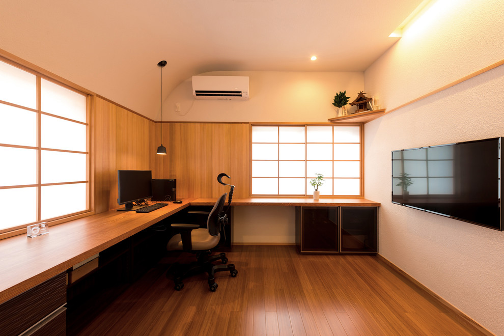 Cette image montre un bureau minimaliste avec un mur blanc, un sol en bois brun, aucune cheminée, un bureau intégré et un sol marron.