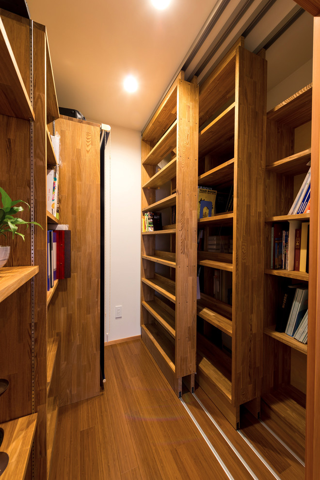 Exemple d'un bureau moderne avec un mur blanc, un sol en bois brun, aucune cheminée, un bureau intégré et un sol marron.
