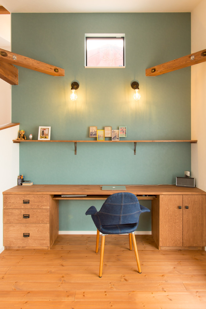 Exempel på ett asiatiskt arbetsrum, med blå väggar, mellanmörkt trägolv, ett inbyggt skrivbord och brunt golv