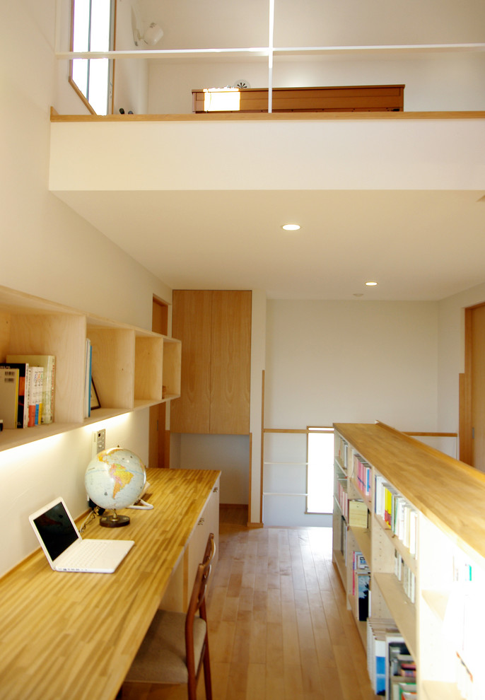 Inspiration för mellanstora moderna arbetsrum, med vita väggar, ljust trägolv, ett inbyggt skrivbord och brunt golv