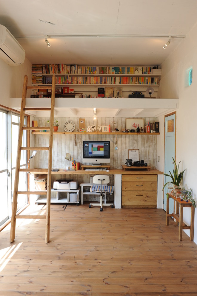 На фото: кабинет в скандинавском стиле с белыми стенами, паркетным полом среднего тона, встроенным рабочим столом и коричневым полом