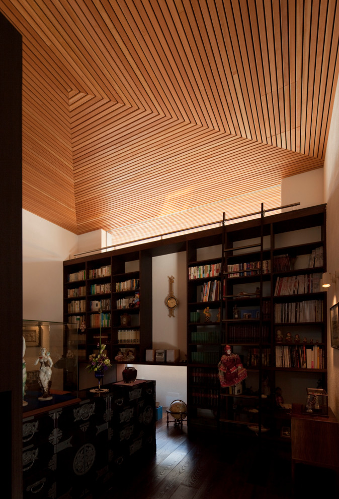 Aménagement d'un bureau moderne de taille moyenne avec une bibliothèque ou un coin lecture, un mur blanc, parquet foncé, aucune cheminée, un bureau intégré et un sol marron.