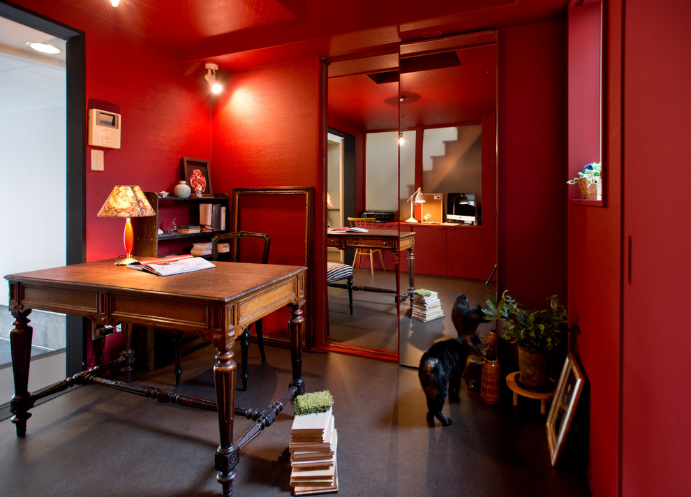 Bild på ett eklektiskt hemmabibliotek, med röda väggar och ett fristående skrivbord
