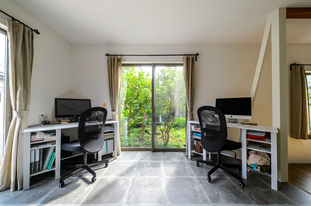 インダストリアルスタイルのおしゃれなホームオフィス・書斎 (白い壁、コンクリートの床、自立型机、グレーの床) の写真