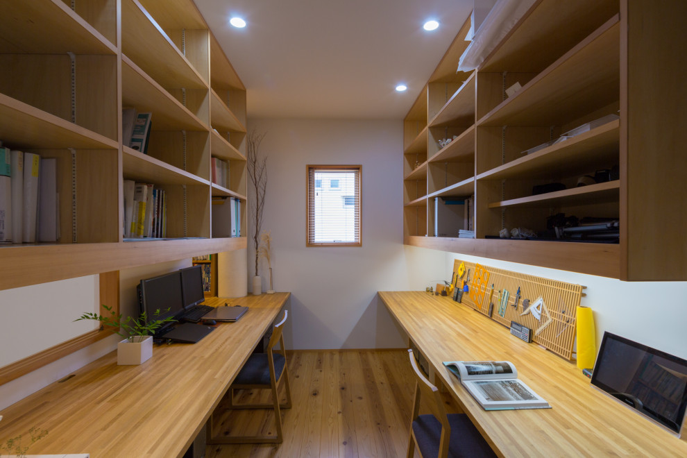 Idées déco pour un petit bureau moderne avec un mur blanc, un sol en bois brun, aucune cheminée, un bureau intégré et un sol beige.