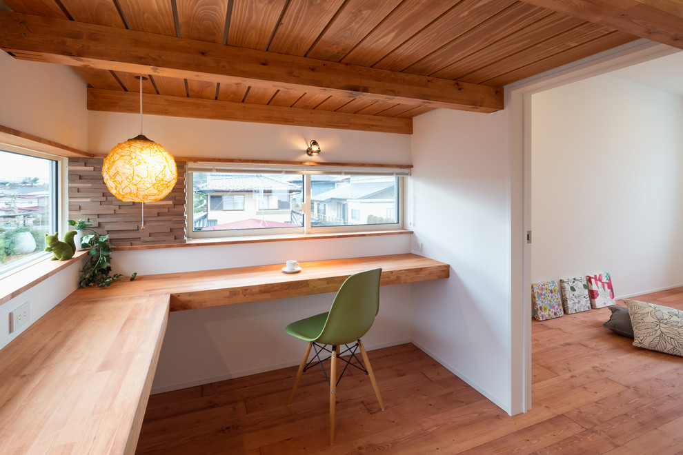 Photo of a world-inspired home office in Other with white walls, medium hardwood flooring, a built-in desk and brown floors.