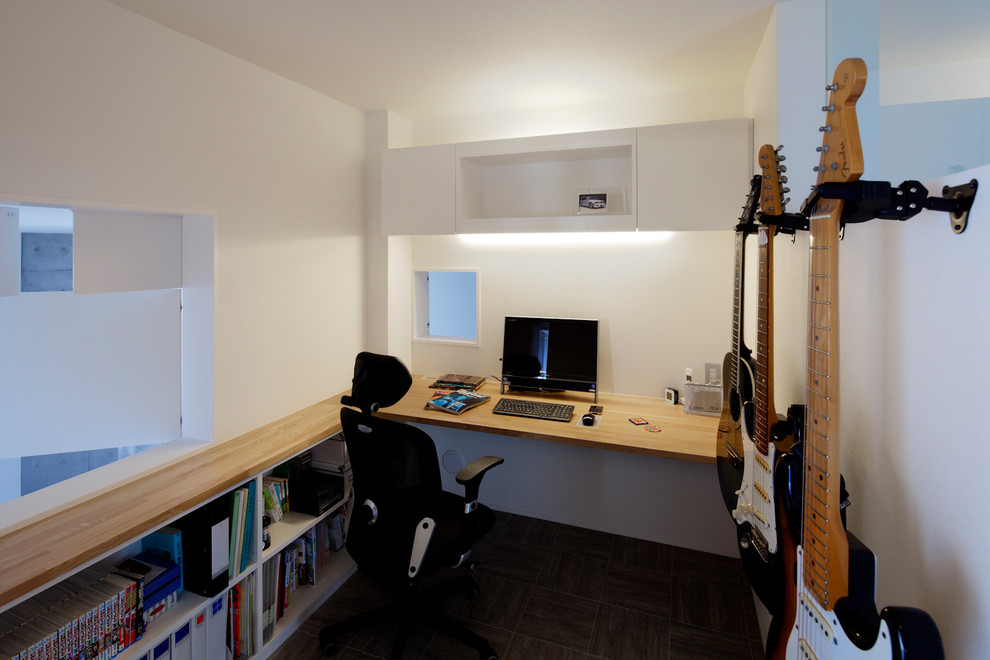 На фото: рабочее место в современном стиле с белыми стенами, паркетным полом среднего тона и встроенным рабочим столом