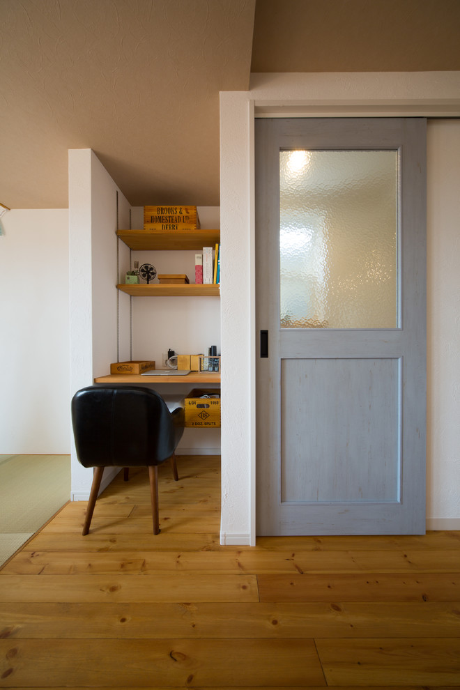 Imagen de despacho nórdico con paredes blancas, suelo de madera clara y escritorio empotrado