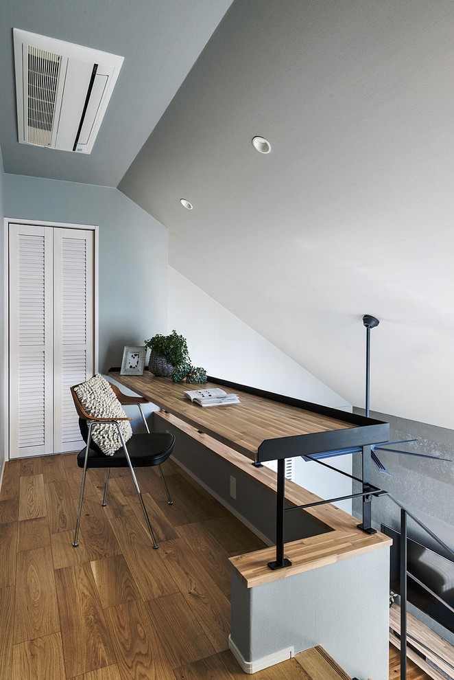 Стильный дизайн: маленький кабинет в скандинавском стиле с серыми стенами, паркетным полом среднего тона, встроенным рабочим столом и коричневым полом для на участке и в саду - последний тренд