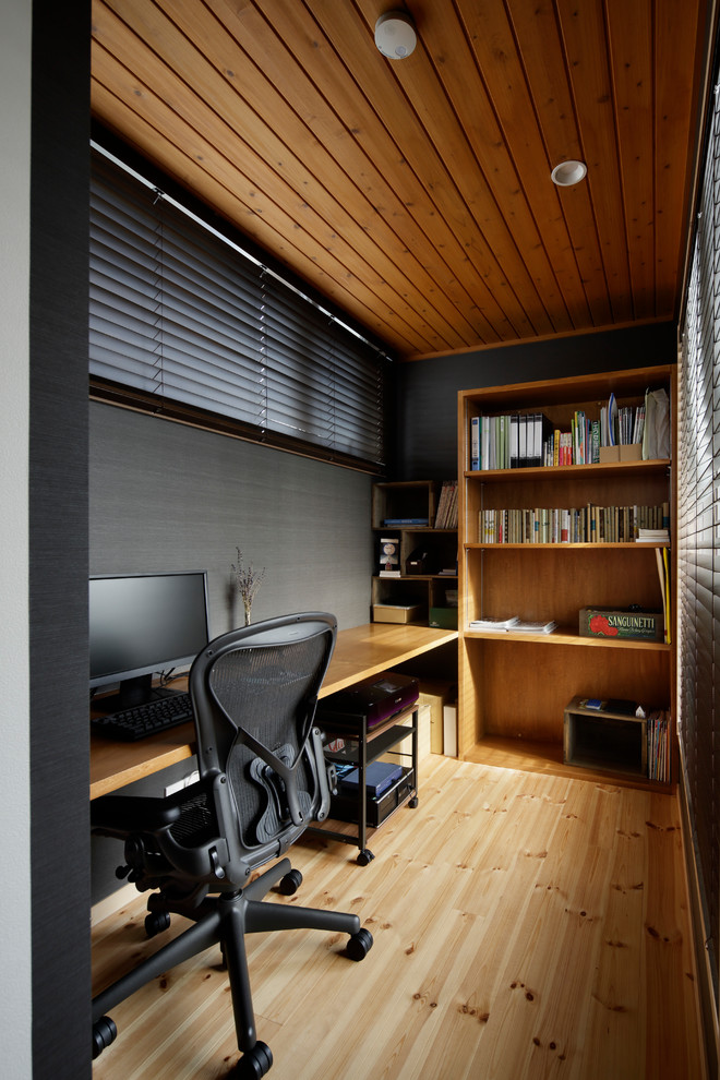 Ejemplo de despacho nórdico pequeño con paredes grises, suelo de madera clara, escritorio empotrado y suelo marrón