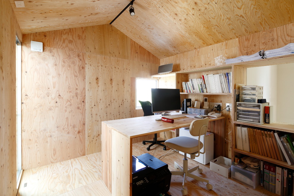 Cette photo montre un bureau industriel avec un mur beige, un sol en contreplaqué, un bureau intégré et un sol beige.