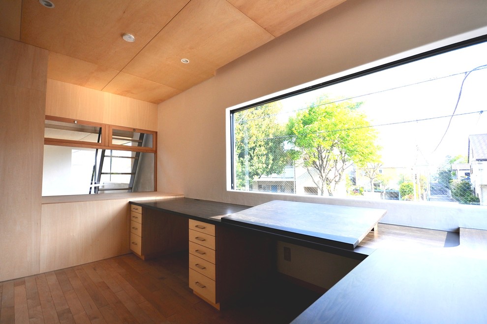 Inspiration pour un bureau minimaliste de taille moyenne et de type studio avec un mur blanc, un sol en bois brun, aucune cheminée, un bureau intégré et un sol marron.