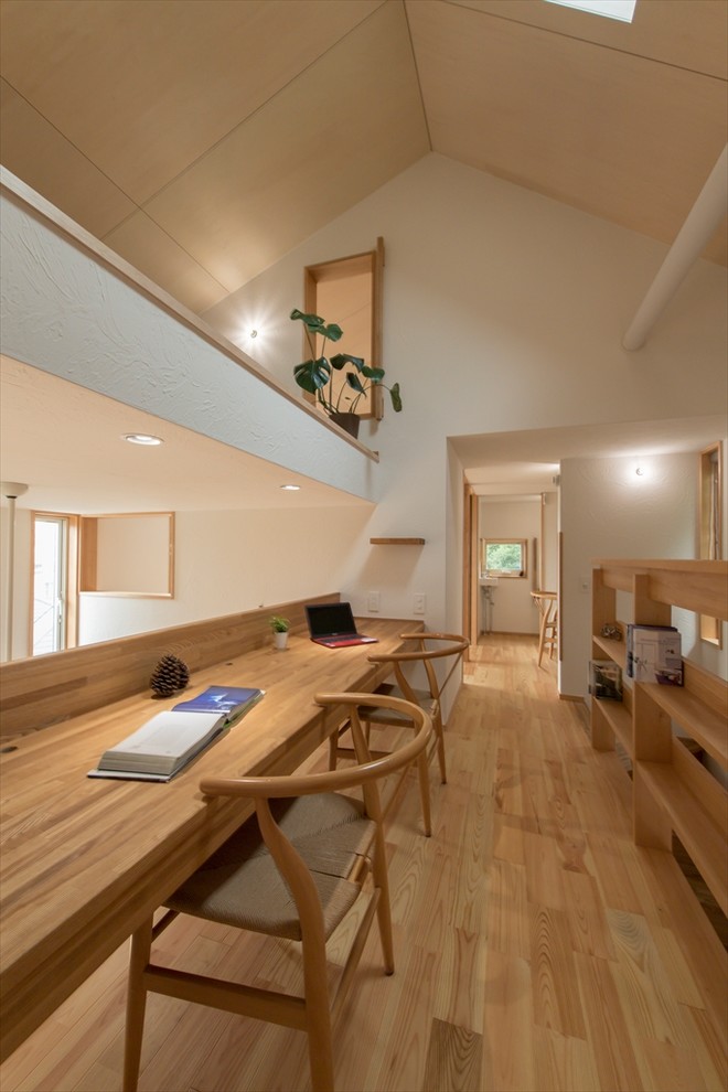 Asiatisches Arbeitszimmer mit weißer Wandfarbe, braunem Holzboden, Einbau-Schreibtisch und braunem Boden in Yokohama