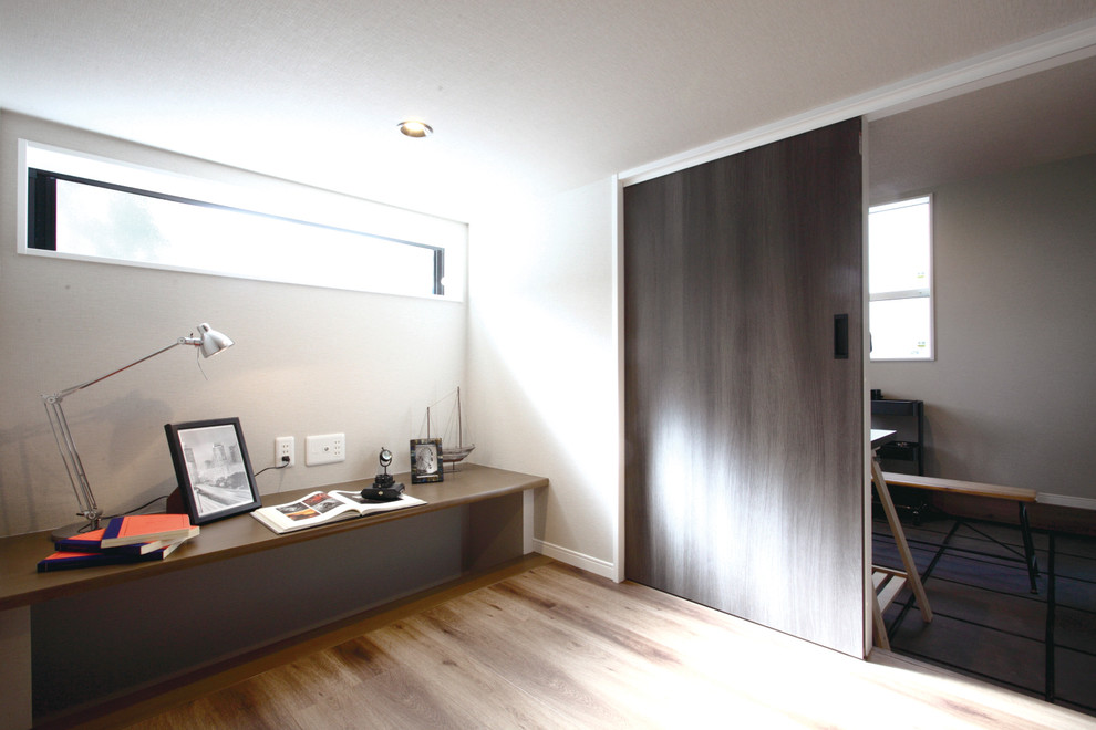 Foto di un ufficio minimalista con pareti bianche, pavimento in compensato, pavimento marrone e scrivania incassata