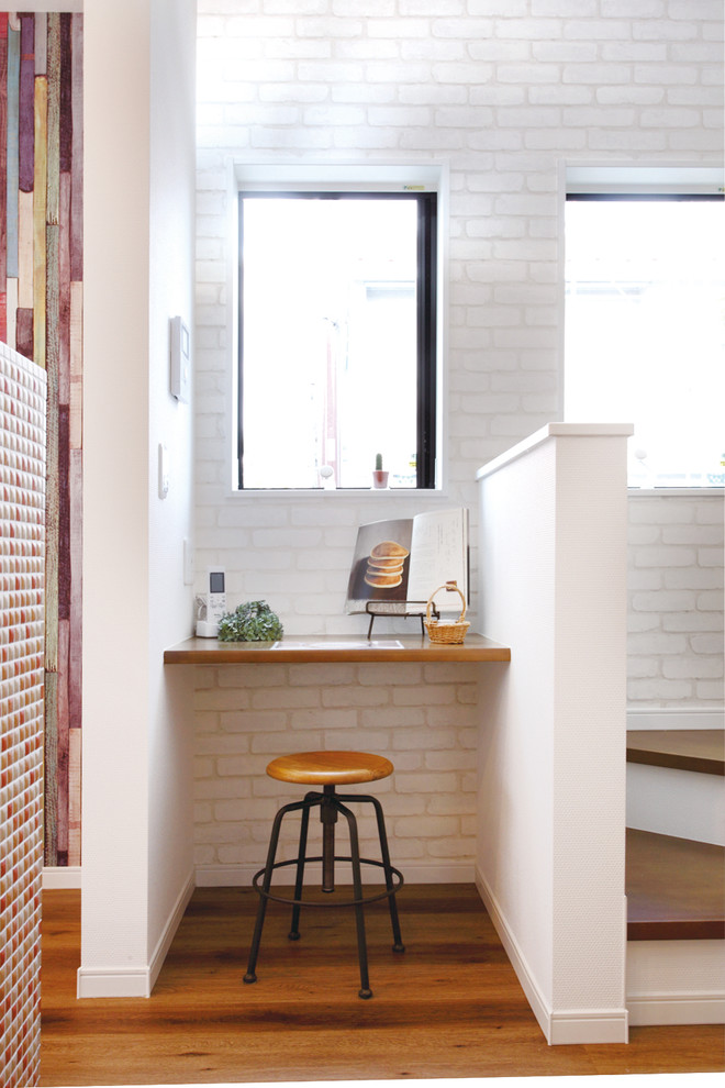 На фото: кабинет в стиле модернизм с разноцветными стенами, полом из фанеры, встроенным рабочим столом и коричневым полом с