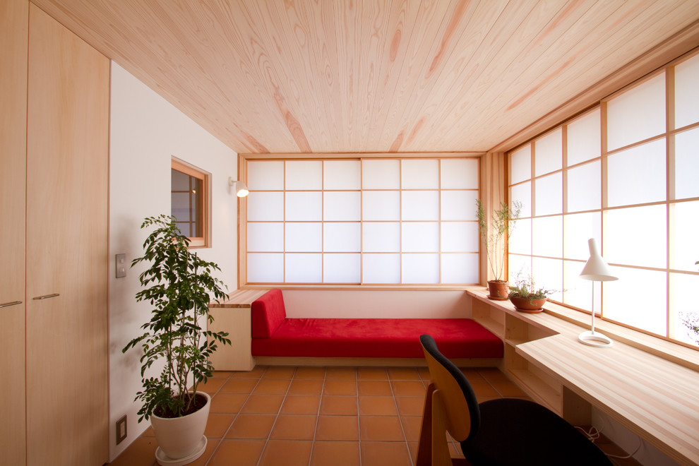 Modelo de despacho de estilo zen con paredes blancas, suelo de baldosas de terracota y escritorio empotrado