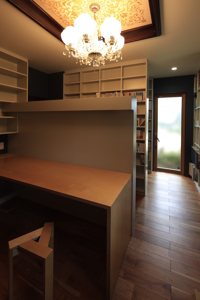 Modelo de despacho asiático con paredes azules, suelo de madera en tonos medios y escritorio empotrado