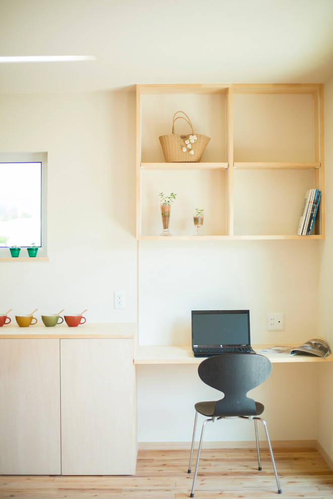 Diseño de despacho escandinavo pequeño sin chimenea con paredes beige, suelo de madera clara y escritorio empotrado