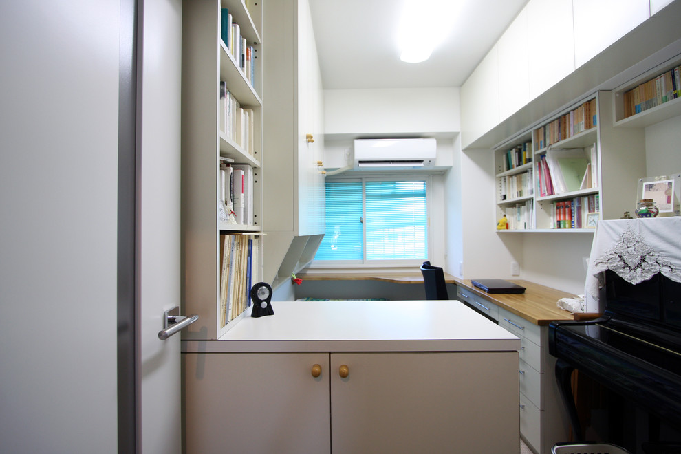 This is an example of a small retro study in Yokohama with white walls, carpet and a built-in desk.