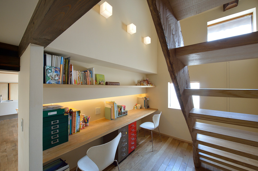 他の地域にあるアジアンスタイルのおしゃれなホームオフィス・書斎 (ベージュの壁、造り付け机) の写真