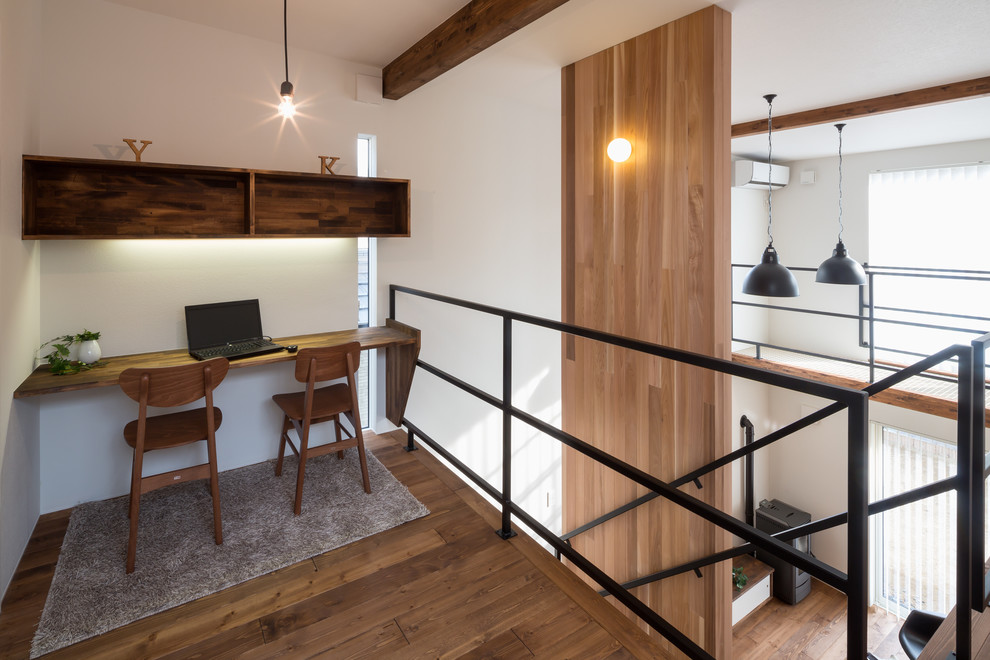 Aménagement d'un bureau contemporain avec un mur blanc, un sol en bois brun, un bureau intégré et un sol marron.