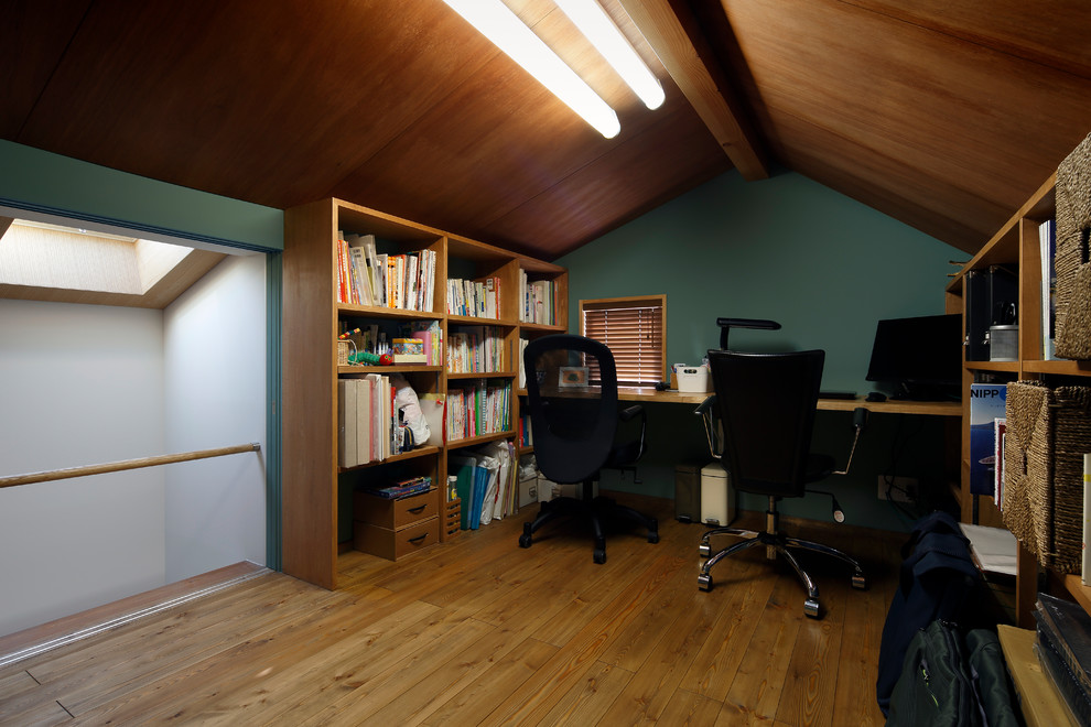 Modernes Arbeitszimmer mit grüner Wandfarbe, braunem Holzboden, Einbau-Schreibtisch und braunem Boden in Tokio Peripherie