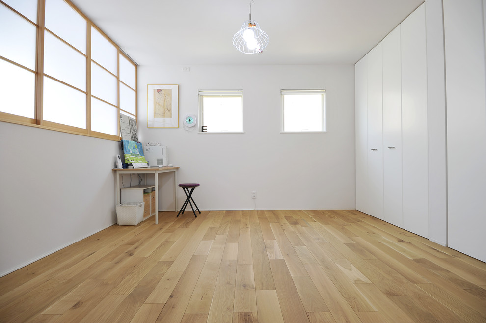 Idee per uno studio scandinavo con pareti bianche, pavimento in legno massello medio e nessun camino