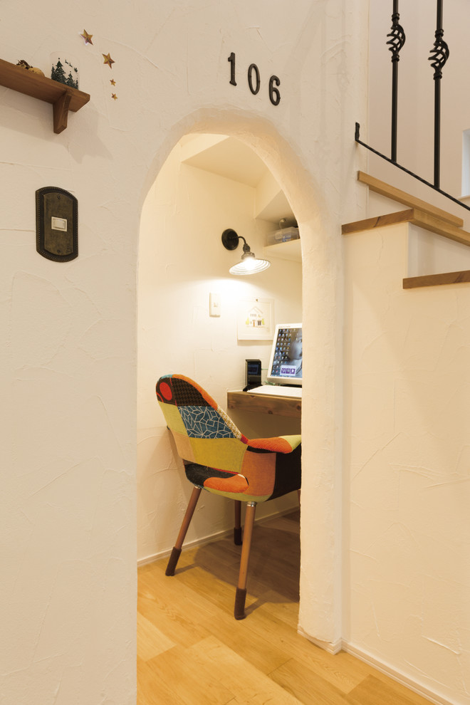 Diseño de despacho mediterráneo pequeño con paredes blancas, suelo de madera clara, escritorio empotrado y suelo beige