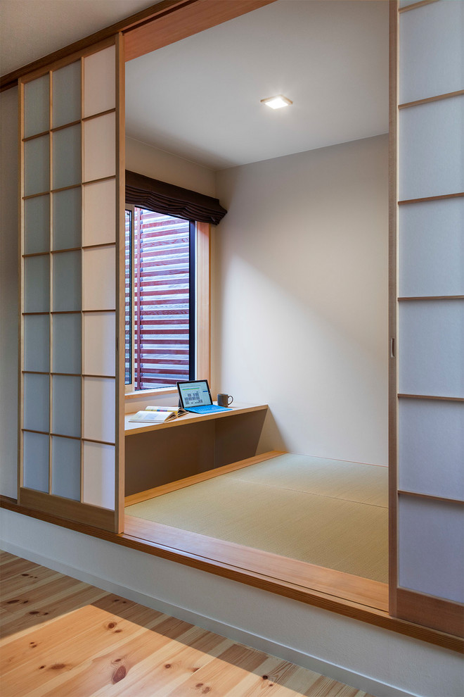 Aménagement d'un bureau moderne avec un mur blanc, un sol de tatami et un bureau intégré.