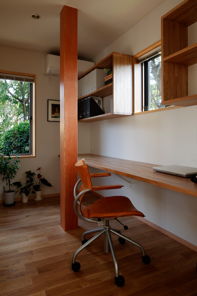 Exemple d'un bureau asiatique avec un mur blanc, un sol en bois brun, un bureau intégré et un sol marron.