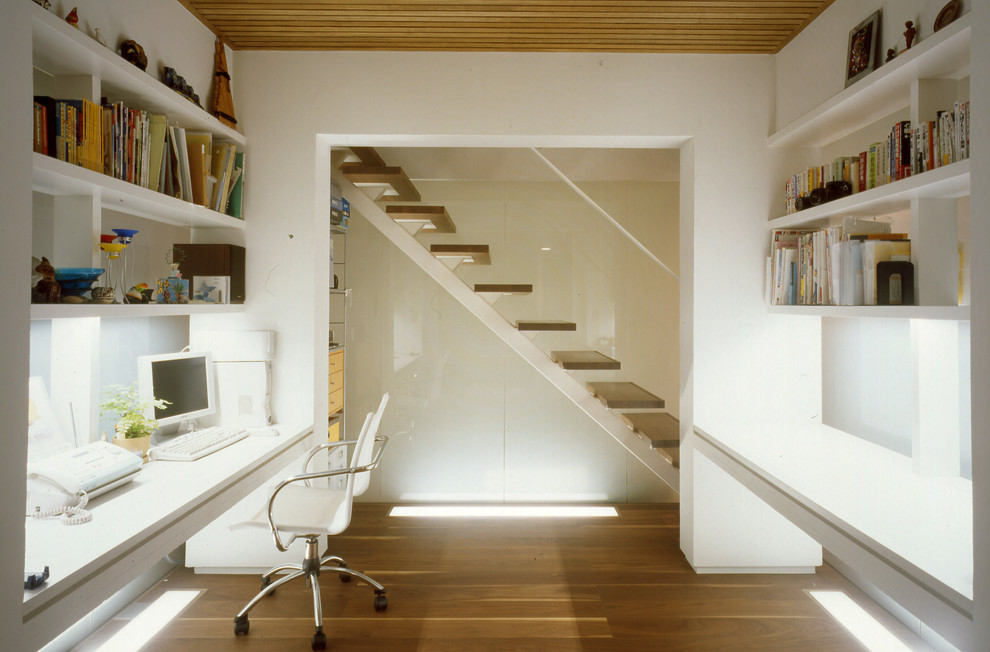 Idee per un ufficio moderno con pareti bianche, pavimento in legno massello medio e scrivania incassata
