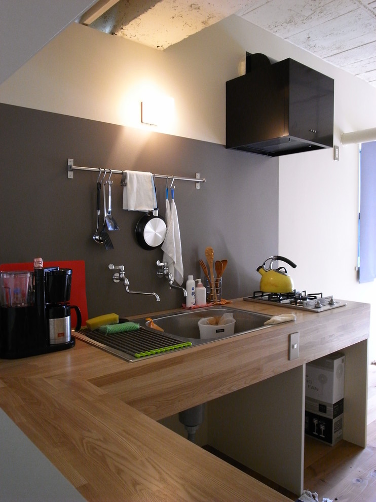 Cette image montre un petit bureau minimaliste de type studio avec un mur beige, un sol en bois brun, un bureau indépendant et un sol marron.