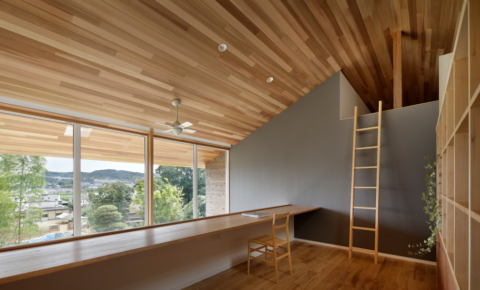 Diseño de despacho nórdico con paredes grises, suelo de madera en tonos medios y suelo marrón