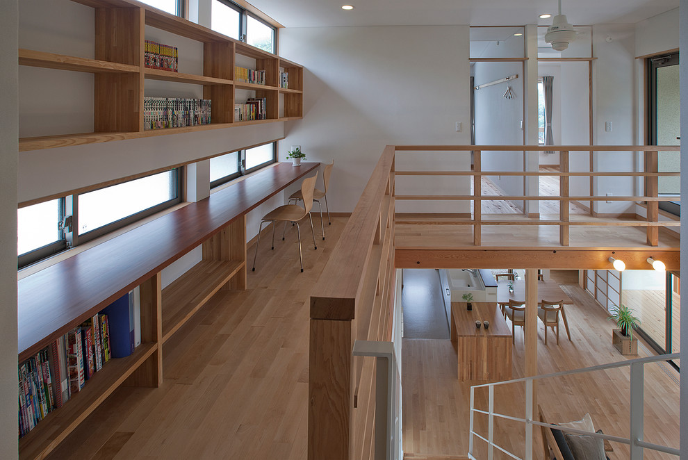 Inredning av ett asiatiskt arbetsrum, med ett bibliotek, vita väggar, ljust trägolv, ett inbyggt skrivbord och beiget golv