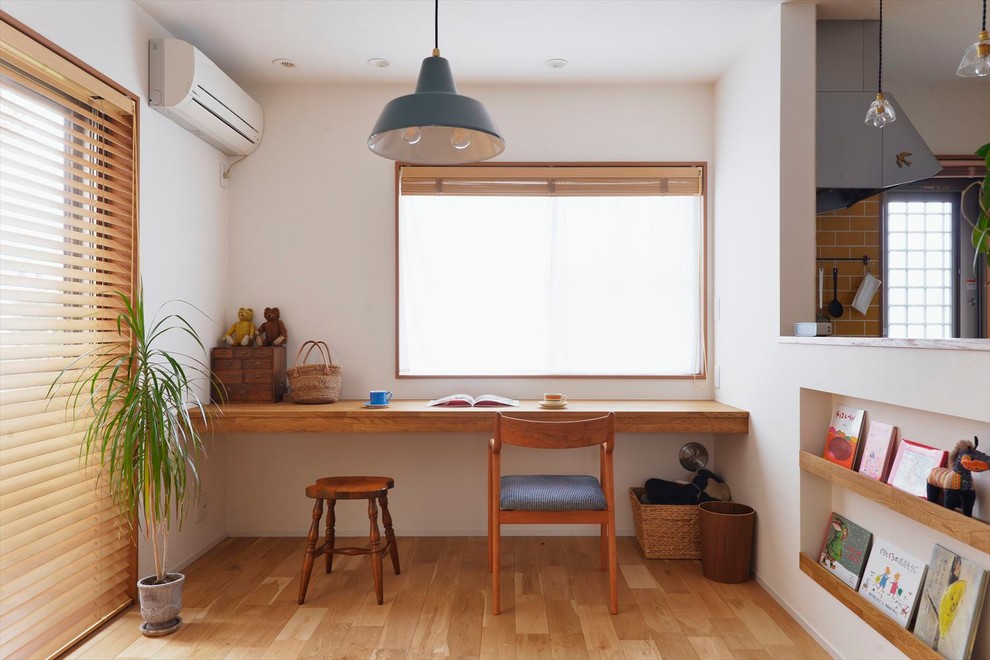 Idee per uno studio country con pareti bianche, pavimento in legno massello medio, scrivania incassata e pavimento marrone