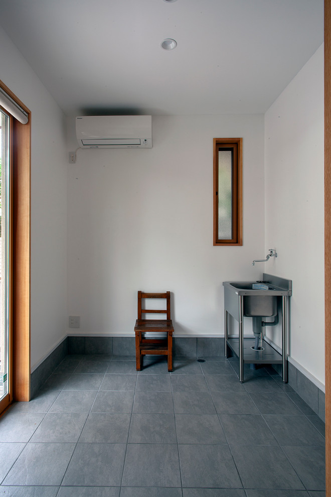 На фото: домашняя мастерская среднего размера в стиле модернизм с белыми стенами, полом из керамогранита, отдельно стоящим рабочим столом и черным полом без камина с